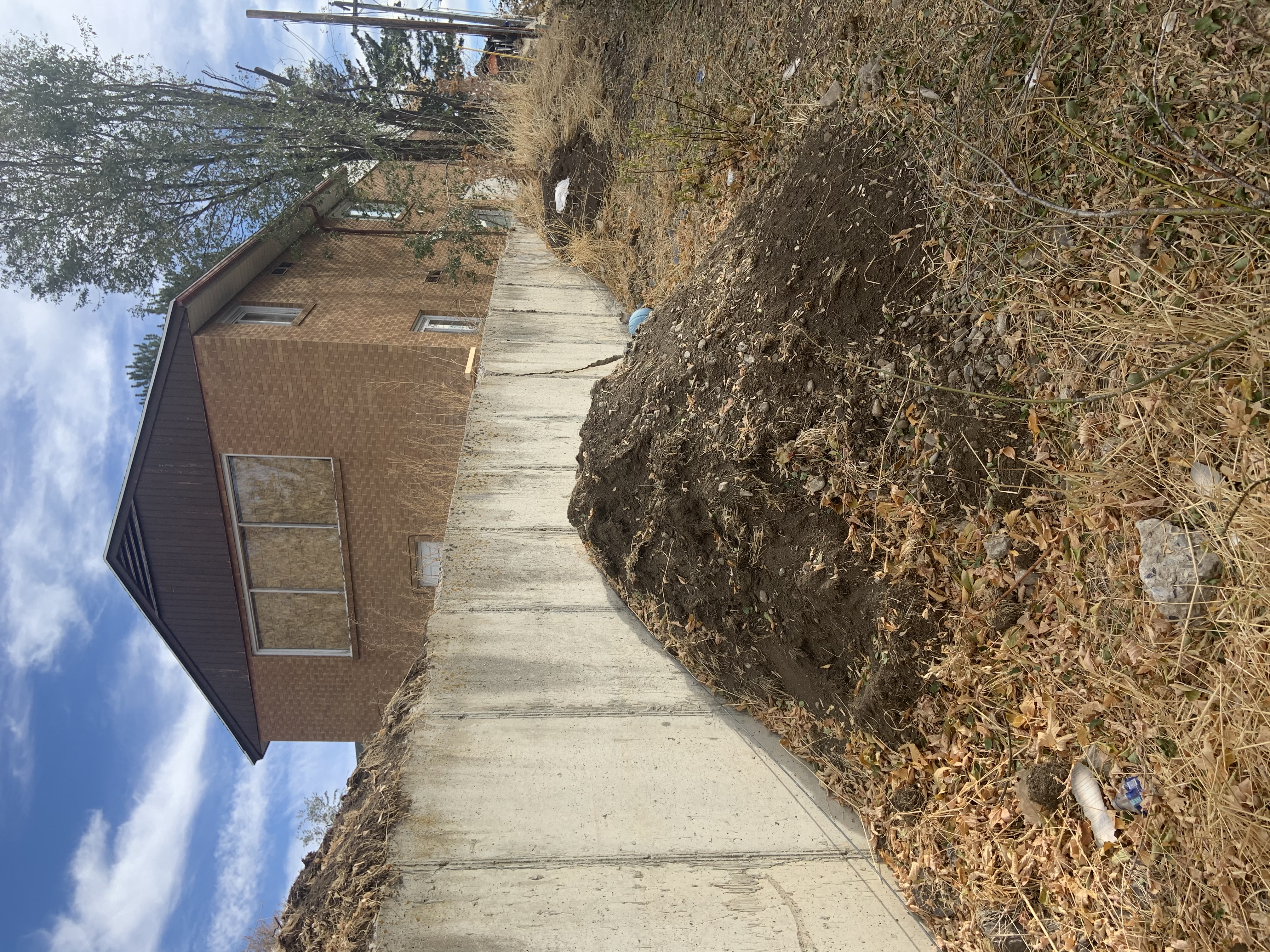 Property before cleanup with dirt and debris along retaining wall